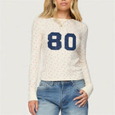 Person wearing a white sweater with blue number '80' and jeans
